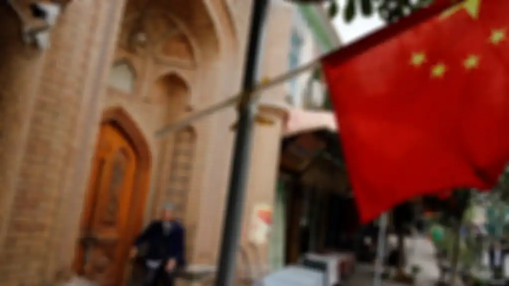 Seorang pria tampak di belakang bendera China di Kota Tua di Kashgar di Wilayah Autonomi Xinjiang Uighur, China, 6 September 2018. 