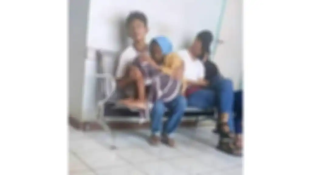 Seorang ibu menggendong ibunya yang tampak sakit.