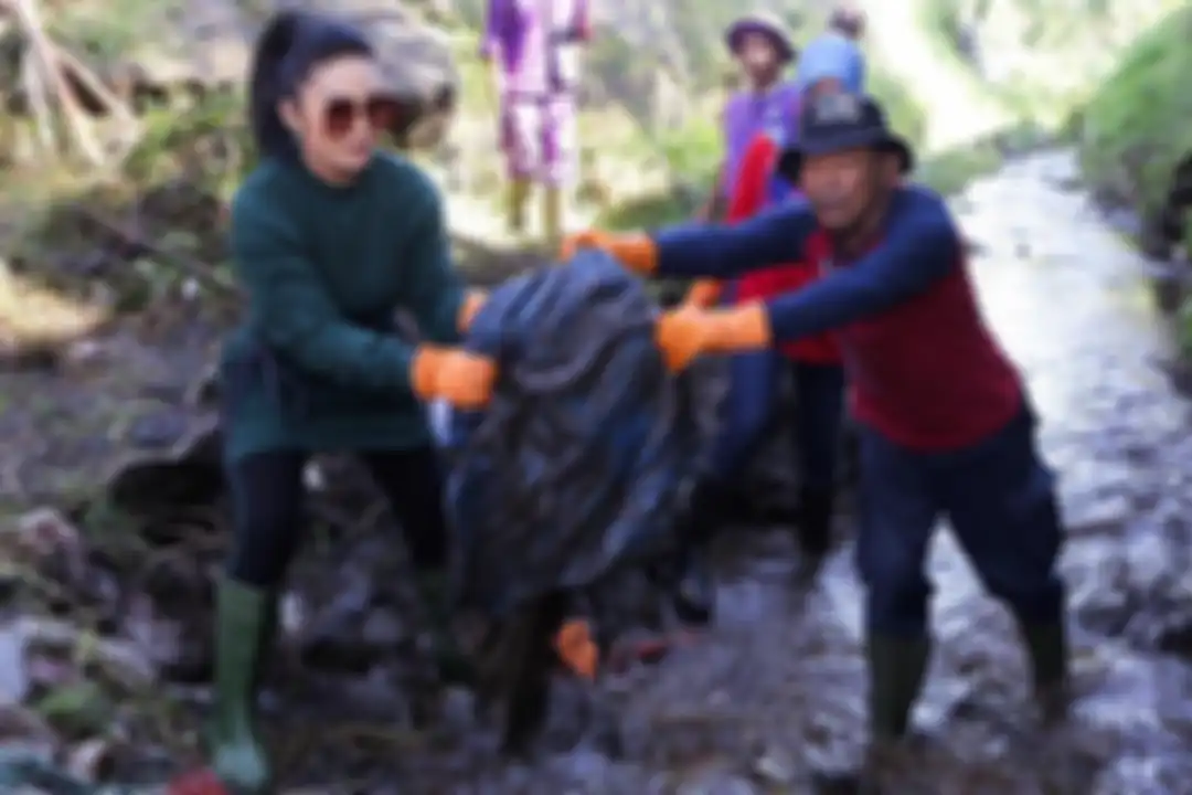 Penampilan Krisdayanti saat membersihkan sampah di sungai