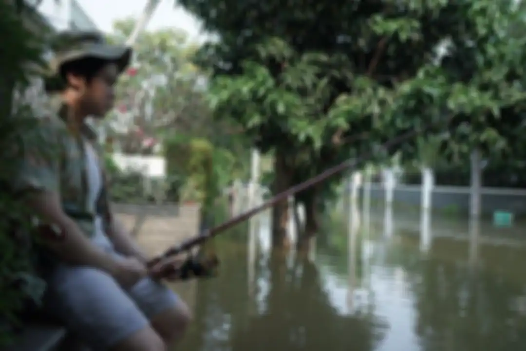 Nicholas Sean yang memancing di depan rumahnya yang terendam banjir air rob.