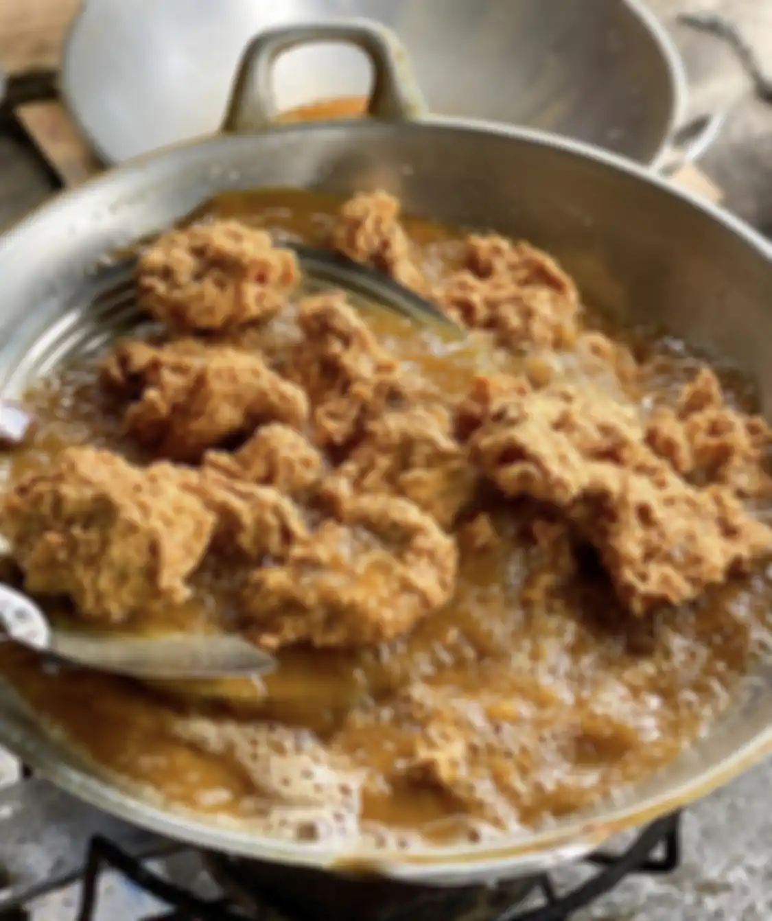Proses menggoreng ayam. Tempat wisata kuliner bernama Ayam Geprek Bu Made menyajikan makan siang enak di Jogja.