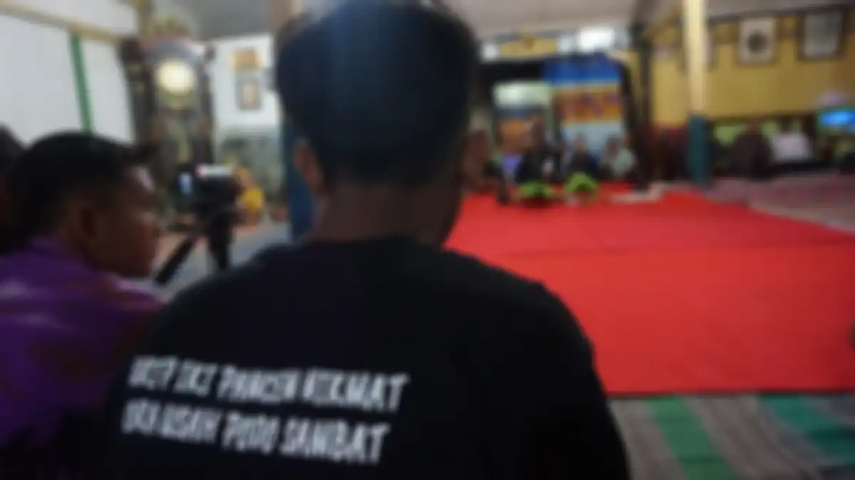 Pengunjung berkaus dengan tulisan norma hidup mengabadikan salah satu prosesi dalam Festival Samin di Dusun Jepang, Margomulyo, Bojonegoro, Jawa Timur, Rabu (11/9/2019) malam.