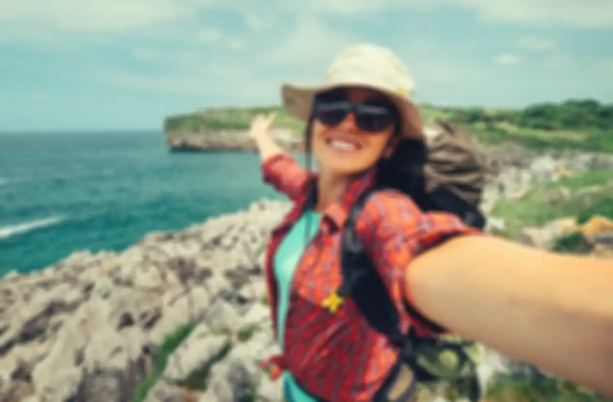 Happy woman backpacker traveler take a selfie photo on amazing ocean coast