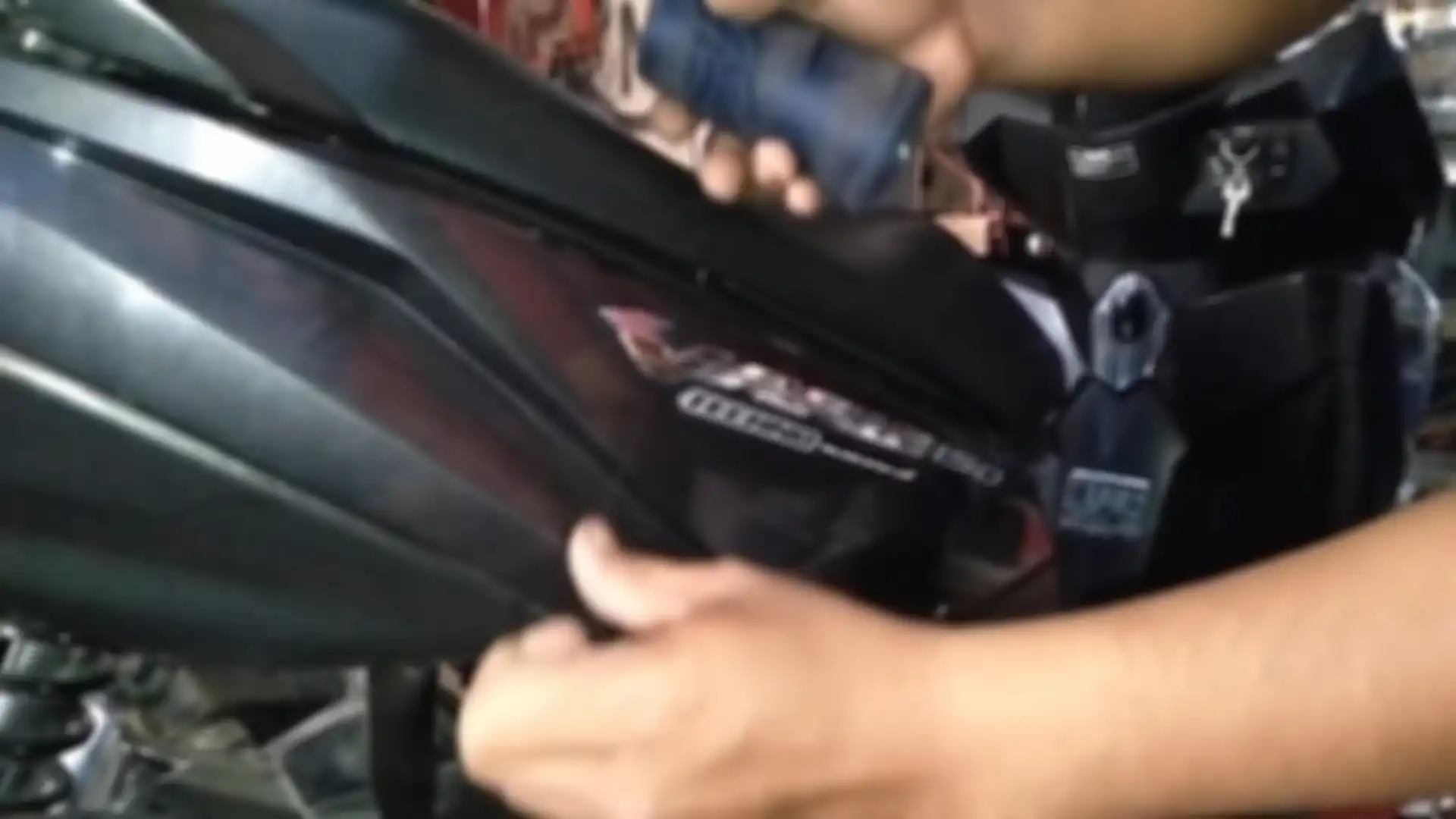 Geser benang ke atas bawah untuk mencopot emblem motor