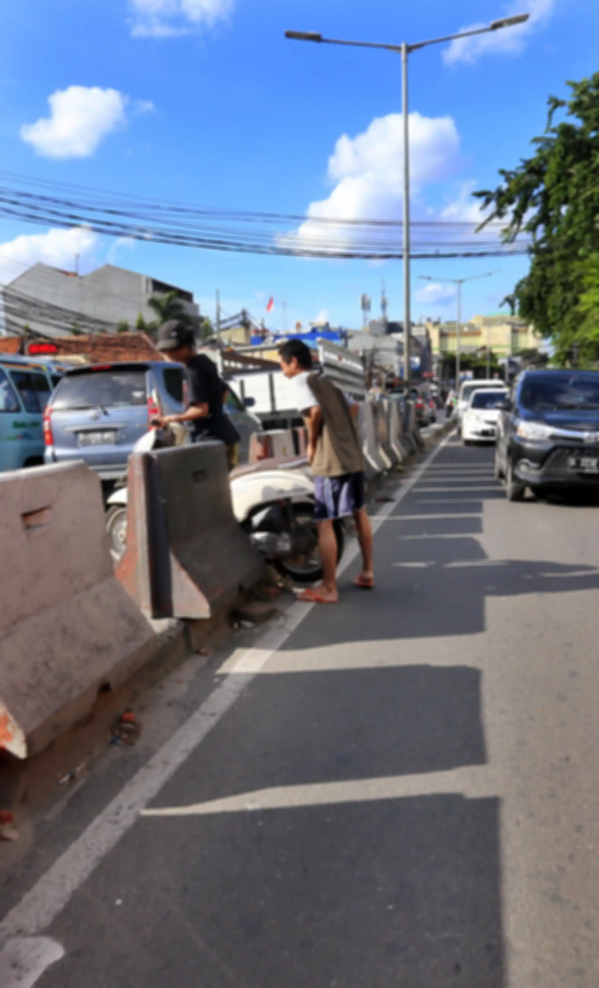 Pengendara sepeda motor dibantu rekannya melintasi separator di Jalan KH Mas Mansyur, Jakarta Pusat,