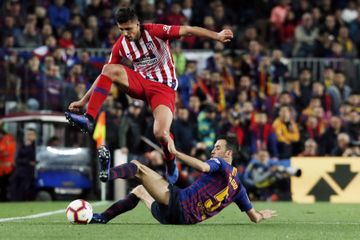Rodri (atas) menghindari tekel Sergio Busquets dalam laga Barcelona versus Atletico Madrid pada lanjutan Liga Spanyol di Camp Nou (6/4/2019).
