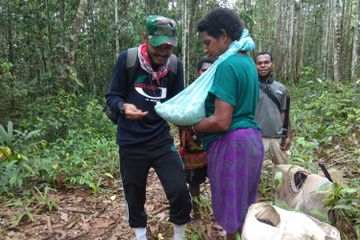 Perawat Tim Nusantara Sehat, Merixz, memberikan imunisasi di tengah hutan kepada seorang bayi berusi
