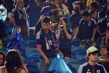 Salah satu suporter Jepang membawa kantung besar untuk membersihkan sampah di stadion.