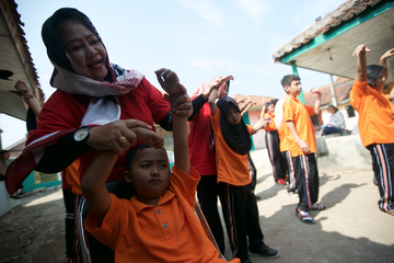Dipandu gurunya, Iksal (11) dipandu gurunya melakukan senam pagi.