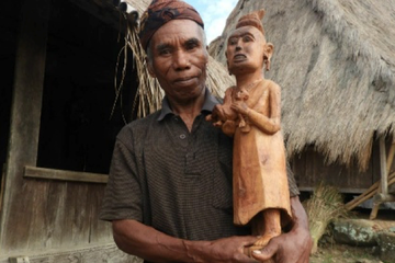 Aloysius Leta Dala (66 tahun) berpose dengan Ine Ria Fai Nggae, hasil seni pahat buatannya sendiri yang terbuat dari kayu nangka. Aloysius merupakan salah satu tetua adat atau mosalaki yang menghuni Kampung Adat Wologai.