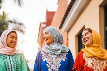 Wanita Muslim yang bahagia berjalan di pusat kota.