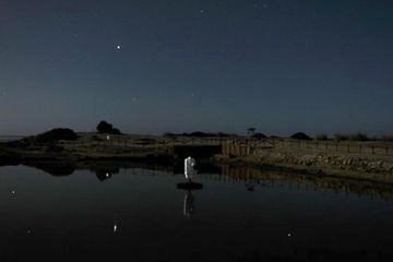 Pemandangan danau buatan di Motya pada malam hari, dengan langit musim dingin merefleksi rasi bintang di kolam air tawar yang suci.