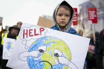 Seorang anak laki-laki memegang papan bertuliskan tolong selama protes untuk keadilan iklim pada 12 November 2022 di Cardiff, Wales. Mayoritas penduduk Eropa masih belum menganggap perubahan iklim.