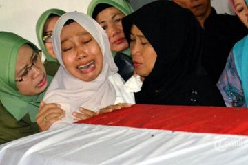 Lina ditemani istri almarhum Praka Suyanto, menangisi peti mati suaminya saat mengikuti acara pemakaman di Magetan 