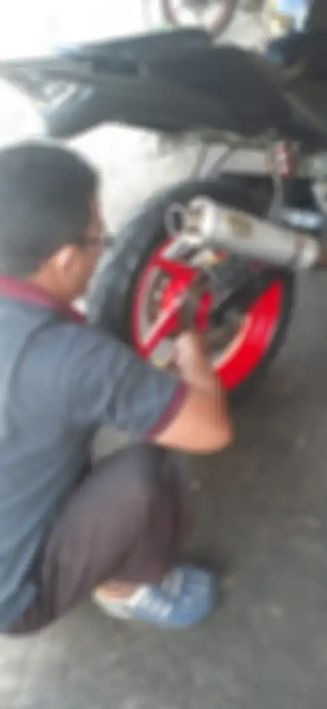 Seorang mekanik sedang mensetel ketegangan rantai 