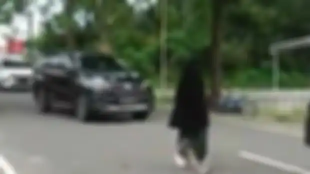 Wanita bercadar terekam kamera video berjalan santai di tengah jalan hingga menimbulkan kemacetan. Polisi ungkap fakta sebenarnya.