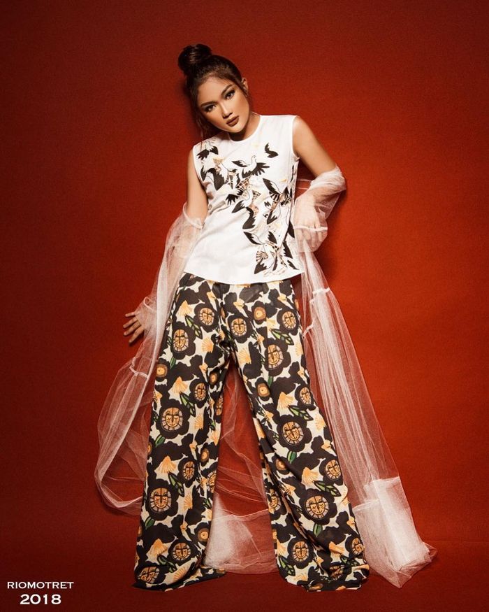 Marion Jola mengenakan sleeveless top bermotif burung-burung yang dipadukan bersama celana kulit bermotif floral