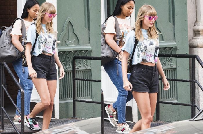 Taylor Swift tampak mengenakan crop top bermotif kitten bernuansa biru yang dipadukan dengan celana hot pants hitam