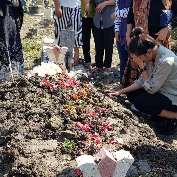 Erie Suzan tertunduk lesu dan menutup matanya saat mengantarkan sang ayah ke pemakaman