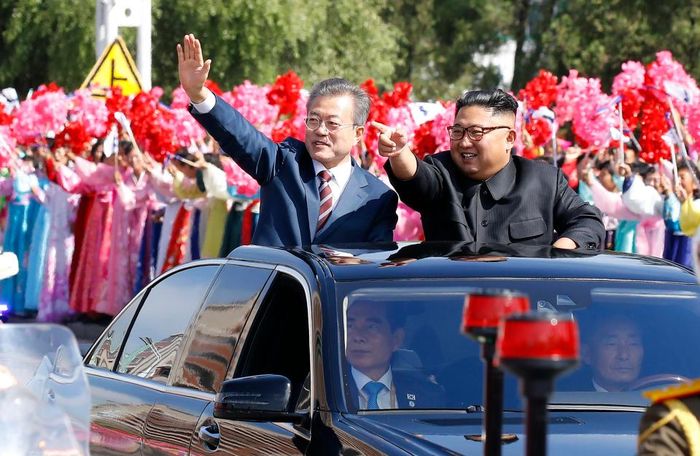 Kim Jong Un dan Moon Jae In melambai dari mobil beratap terbuka