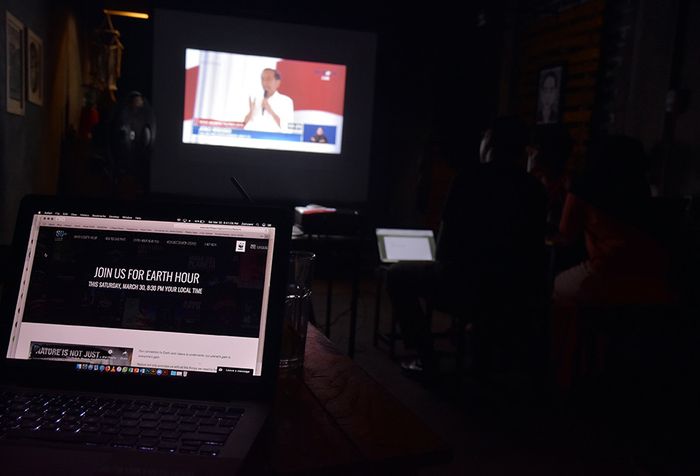 Sejumlah pengunjung menonton debat Calon Presiden 2019 keempat dalam kondisi gelap saat kampanye global 'Earth Hour' di Kedai Kopikirapa, Kota Pekanbaru, Riau, Sabtu (30/3/2019). Warga dan pelaku usaha di Pekanbaru mematikan lampu selama satu jam dari pukul 20.30 hingga 21.30 WIB pada gerakan kampan
