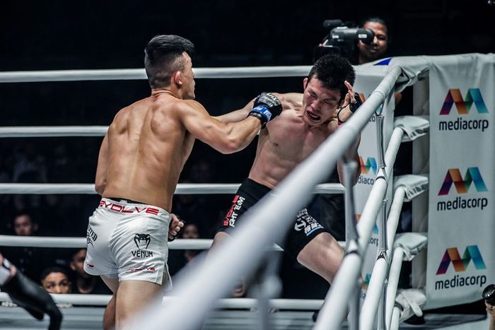 Atlet asal Singapura, Christian Lee (kiri), melepaskan pukulan ke arah petarung Jepang, Shinya Aoki, dalam ajang ONE: Enter The Dragon di Singapura, Jumat (17/5/2019).