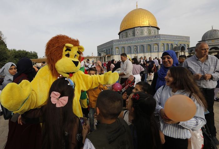 Muslim Palestina tersenyum melihat orang berkostum singa, seusai menunaikan Shalat Id di Kota Tua Yerusalem, 5 Juni 2019.