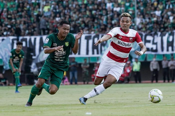 Pemain Madura United, Asep Berlian (kanan), berebut bola dengan Oktafianus Fernando, gelandang Persebaya (kiri) pada leg pertama babak 8 besar Piala Indonesia 2018 di Stadion Gelora Bung Tomo, Surabaya, Rabu (19/6/2019).