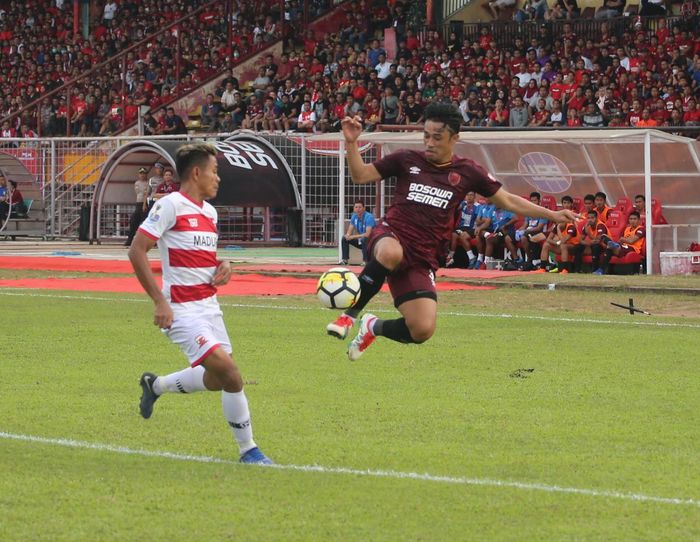 Bek sayap PSM Makassar, Beny Wahyudi melakukan kontrol bola di udara dan diawasi gelandang Madura United, Asep Berlian pada semifinal pertama Piala Indonesia 2018 di Stadion Andi Mattalatta, Kota Makassar, 30 Juni 2019.