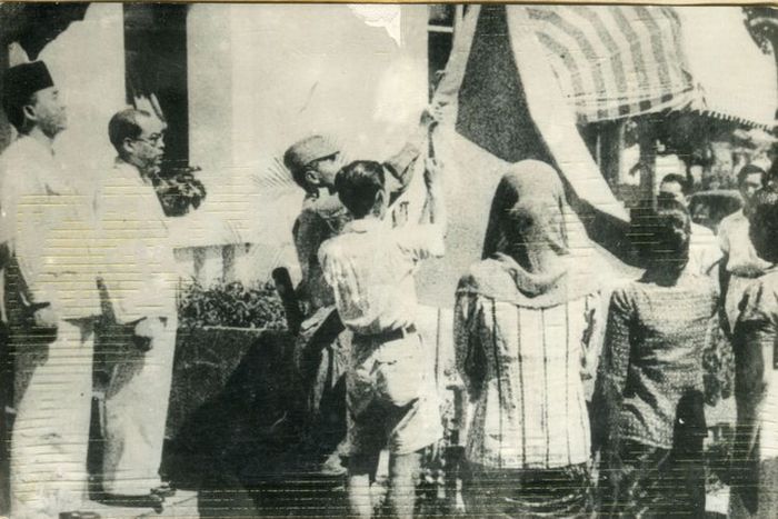 Upacara penaikan bendera sang merah putih di halaman gedung pegangsaan timur 56 (Gedung Proklamasi). Tampak antara lain Bung Karno, Bung Hatta, Let,Kol. Latief Hendraningrat (menaikkan bendera) Ny. Fatmawati Sukarno dan Ny.S.K Trimurti.