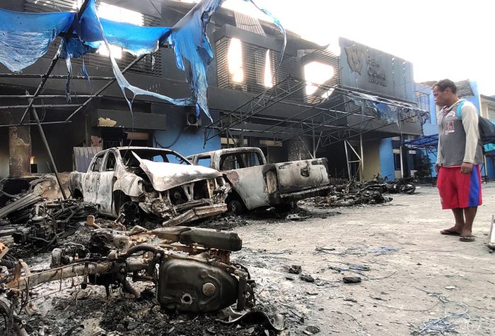 Seorang warga mengamati Kantor Bea Cukai Papua serta sejumlah mobil yang terbakar saat berlangsungnya aksi unjuk rasa di Jayapura, Papua, Jumat (30/8/2019). Sejumlah bangunan dan kendaraan terbakar saat aksi pada (29/8/2019). Sejumlah bangunan dan kendaraan terbakar saat aksi unjuk rasa yang berakhi