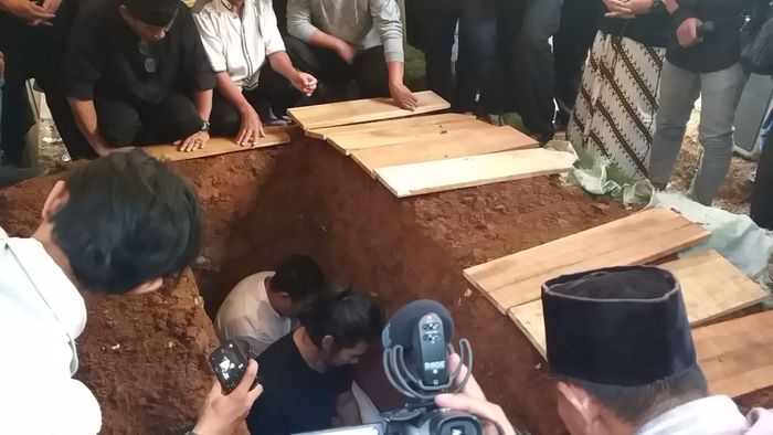 Donny Alamsyah membantu memasukkan jenazah sang ayahanda ke liang lahat 