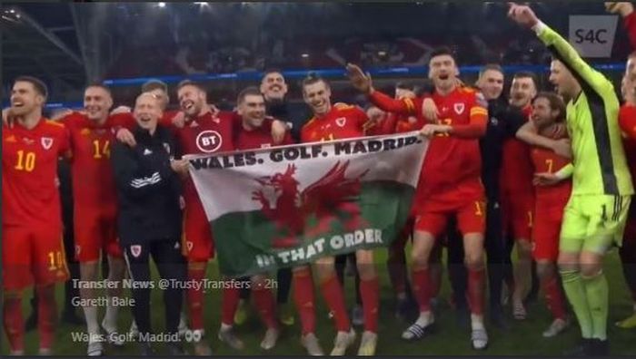 Pemain sayap timnas Wales, Gareth Bale, membawa bendera sindiran untuk klubnya, Real Madrid, saat merayakan kelolosan ke Piala Eropa 2020.