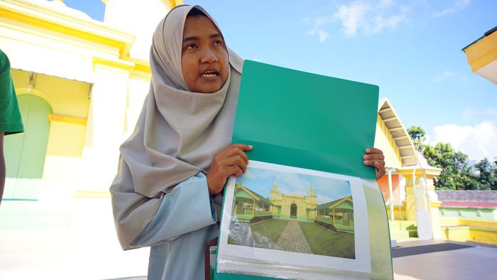 Nurfatilla Afidah, intepreter Tur Masjid Raya Sultan Riau, menunjukkan foto Masjid Sultan Riau Penyengat saat dirinya masih kecil.