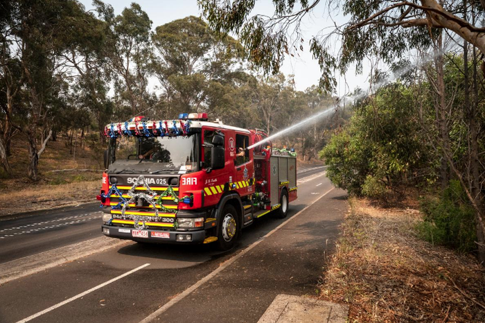 Petugas pemadam kebakaran dari Metropolitan Fire Brigade Melbourne menyemprotkan air pada kelelawar yang berkumpul di batang pohon di Yarra Bend Park agar mereka merasa lebih dingin. 