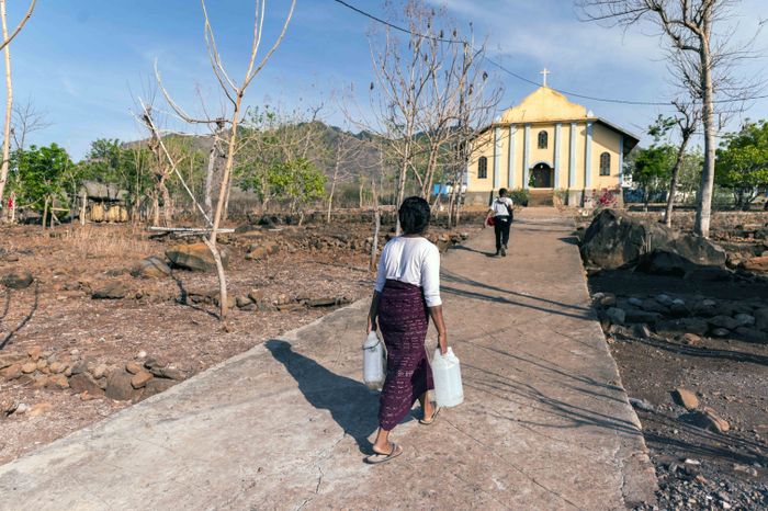 Seorang mama berjalan sembari menenteng jeriken menuju kran air yang berada di pekarangan samping kapel dusun. Air tak tersedia setiap hari, sehingga sebagian kebutuhan air dipenuhi dengan membeli dari pemasok air keliling.