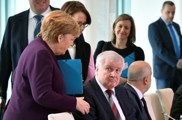 Kanselir Jerman, Angela Merkel, mengulurkan tangannya untuk berjabat tangan dengan Menteri Dalam Negeri Horst Seehofer.