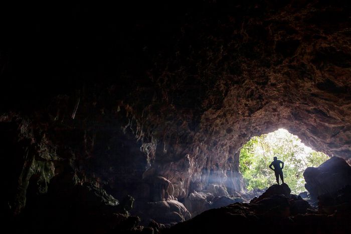 Seorang pria berdiri di mulut di atas batu-batu dalam Ngalau Talago.