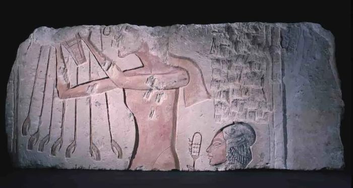 Akhenaten dan salah satu putrinya, memegang sistrum, memberikan persembahan kepada Aten, yang memberkati mereka dengan sinarnya.