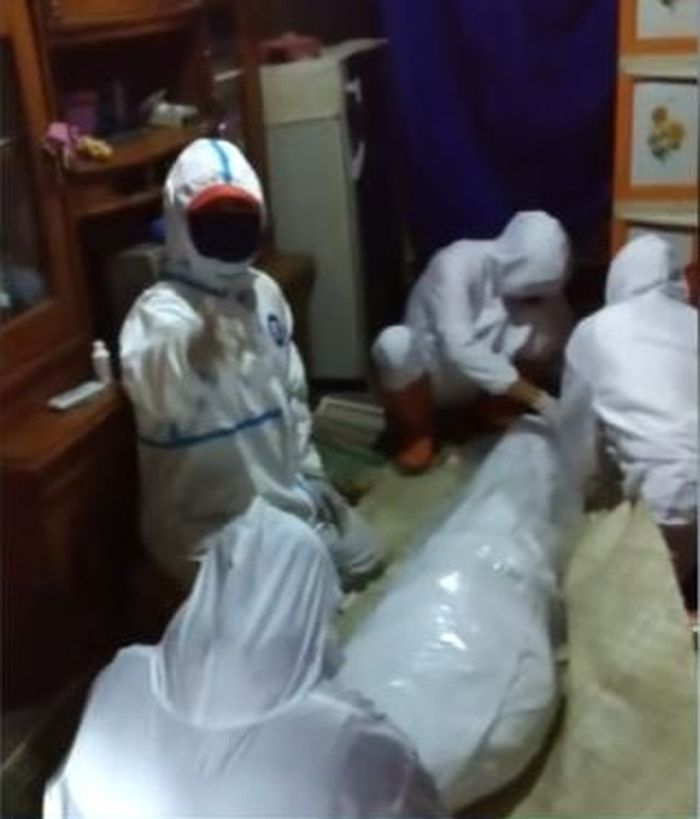 Tim pemulasaran jenazah Covid-19 membungkus pasien yang meninggal dunia dengan plastik bening biasa.