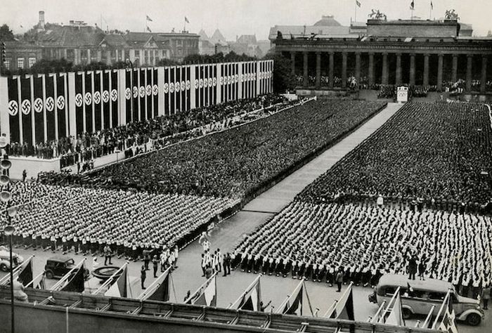 Api Olimpiade tiba di stadion yang dipenuhi swastika pada Upacara Pembukaan Olimpiade Berlin 1936. Meskipun banyak seruan untuk boikot atas kebangkitan Adolf Hitler dan antisemitisme, Olimpiade Berlin tetap berlangsung—tetapi merupakan yang terakhir selama lebih dari satu dekade karena Perang Dunia II.