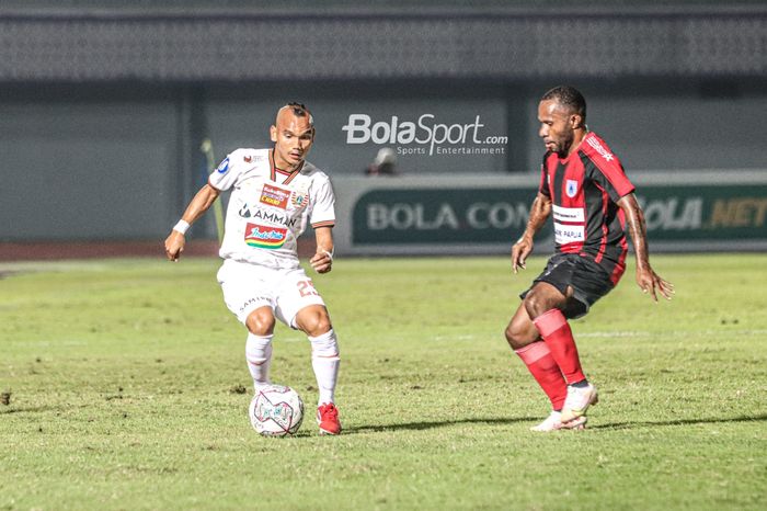 Pemain sayap kanan Persija Jakarta, Riko Simanjuntak (kiri), sedang menguasai bola dan dibayangi pilar Persipura Jayapura, Yohanes Pahabol (kanan), Pelatih Persipura Jayapura, Jaksen F Tiango, sedang memantau para pemainnya dalam laga pekan ketiga Liga 1 2021 di Stadion Indomilk Arena, Tangerang, Ba