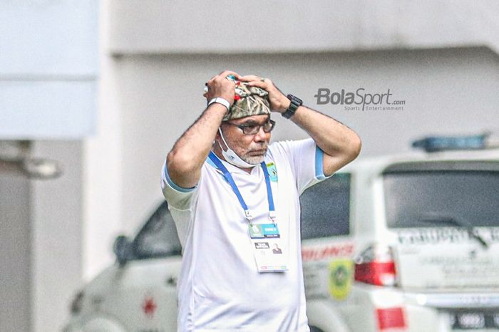 Pelatih Persela Lamongan, Iwan Setiawan, sedang memegangi peci yang melekat di kepalanya dalam laga pekan kelima Liga 1 2021 di Stadion Pakansari, Bogor, Jawa Barat, 28 September 2021.