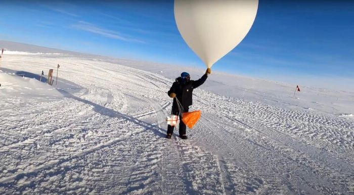 Seorang ilmuwan meluncurkan balon cuaca yang membawa ozonesonde dari Stasiun Kutub Selatan pada Maret 2021.