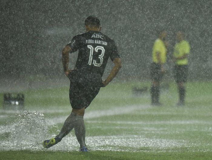Winger Persib Bandung, Febri Hariyadi, mencoba menyingkirkan air yang menggenangi lapangan saat laga melawan Persiraja Banda Aceh pada pekan ke-29 Liga 1 2021-2022.