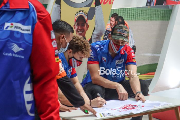 Dua pembalap Mandalika Racing Team Indonesia (Pertamina Mandalika SAG), Bo Bendsneyder (kanan) dan Gabriel Rodrigo (tengah), sedang menandatangani baju di Epicentrum, Kuningan, Jakarta, 10 Maret 2022.