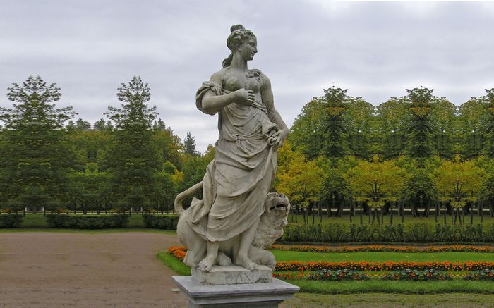 Dewi Libertas bersama seekor kucing mengitari kakinya di taman Istana Pavlovsk.