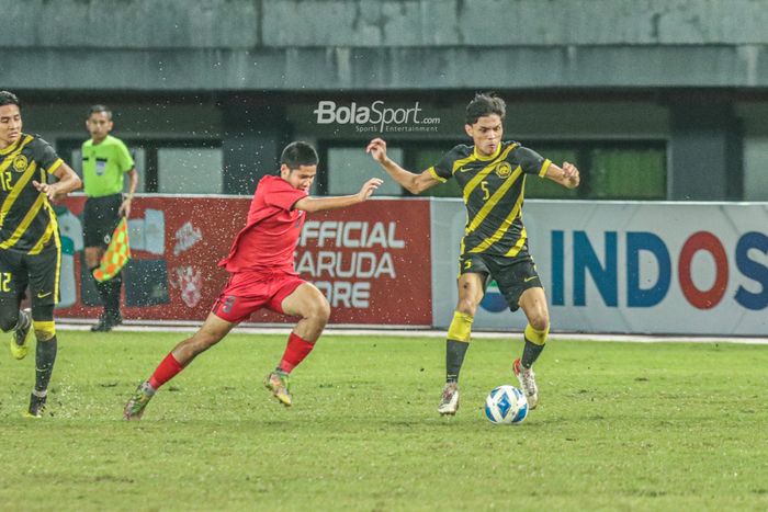 Pemain timnas U-19 Malaysia, Muhammad Faiz Amer Runnizar (kanan), sedang menguasai bola dan dibayangi pilar timnas U-19 Laos bernama Safyon Keohanam (kiri) saat bertanding di Stadion Patriot Candrabhaga, Bekasi, Jawa Barat, 15 Juli 2022.