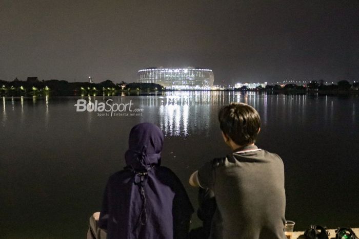 Dua sejoli sedang bercengkrama dengan pemandangan Jakarta Internasional Stadium (JIS) di Danau Cincin, Jakarta Utara, 28 September 2022.