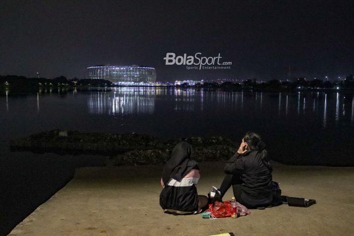 Dua pengunjung sedang memandangi Jakarta Internasional Stadium (JIS) di Danau Cincin, Jakarta Utara, 28 September 2022.